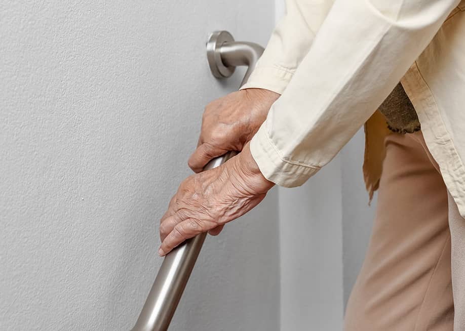 A senior woman holding onto a handrail to safely walk down the stairs. — Toa55 // Shutterstock