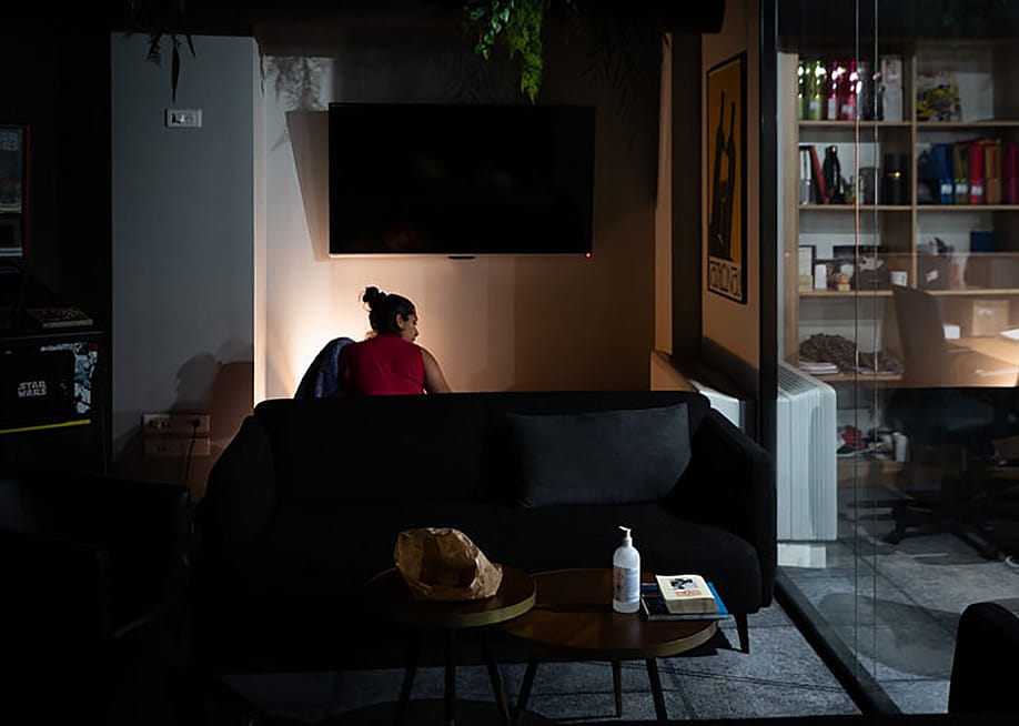A young woman settling in at night to sleep at an office space's sofa. — Béatrice Prève