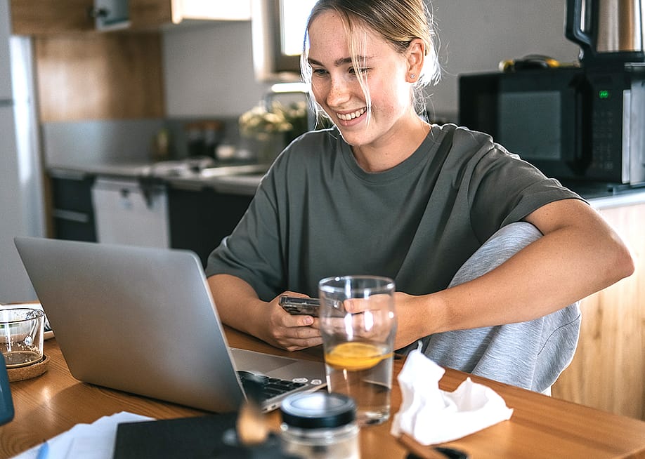 A young adult working remotely at her cozy kitchen at home. — Shyntartanya // Shutterstock