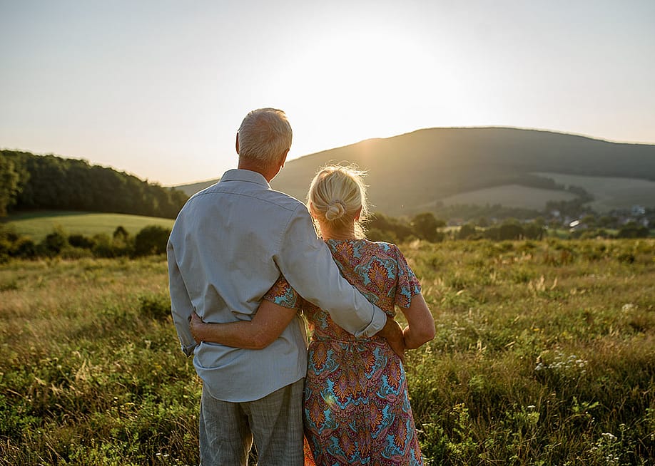 An elderly married couple enjoying the sunset view after a walk. — Halfpoint // Shutterstock