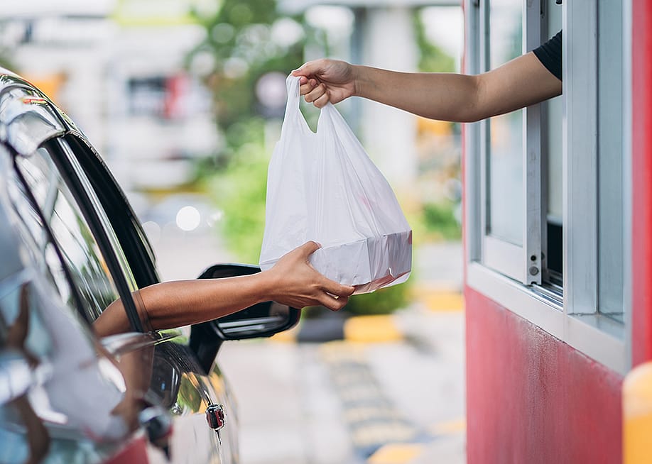 Person receiving their takeaway order at the drive thru. — NewJadsada // Shutterstock