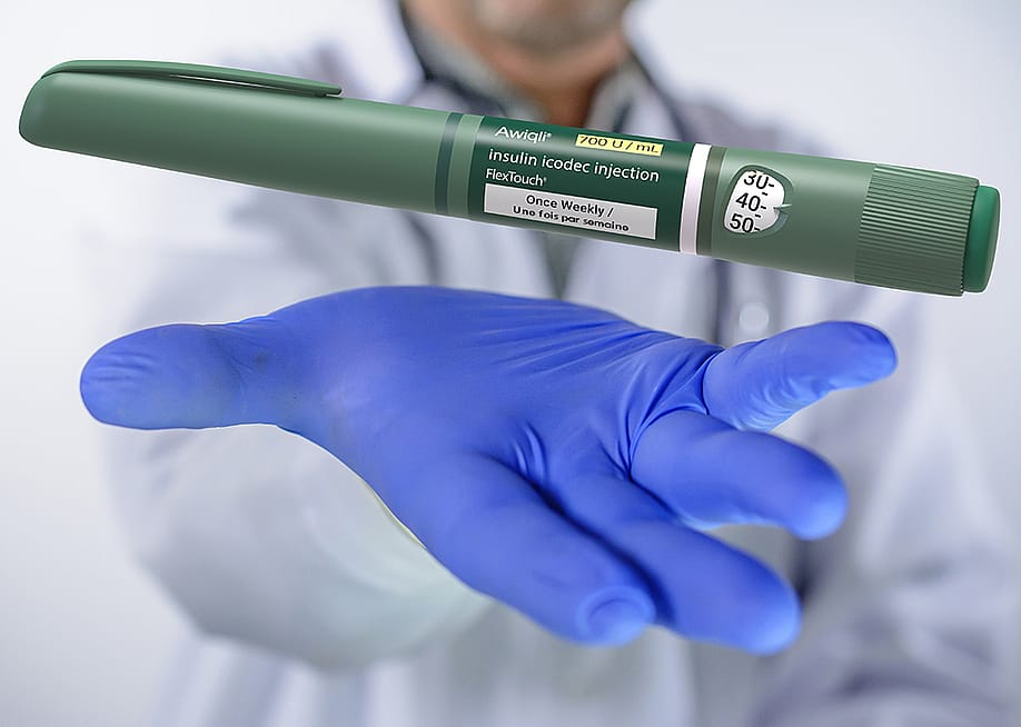 A doctor gesturing to hold an insulin icodec injection pen. — Giovanni Cancemi // Shutterstock