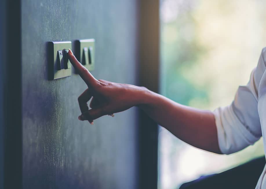 Person turning off a light switch at home. — Panumas Yanuthai // Shutterstock