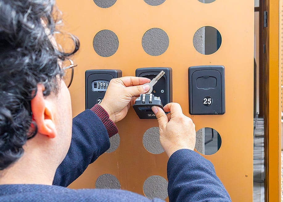 Person accessing key storage boxes. — JairoMZ // Shutterstock