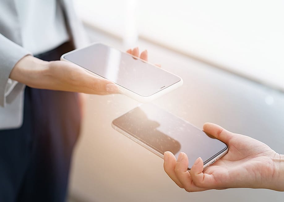 Two people's phones connecting via sync to exchange information. — maruco // Shutterstock
