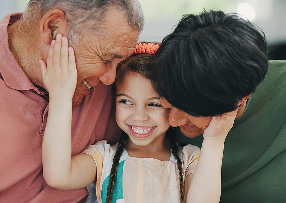 Grandparents happily bonding with their young granddaughter. — PeopleImages // Shutterstock