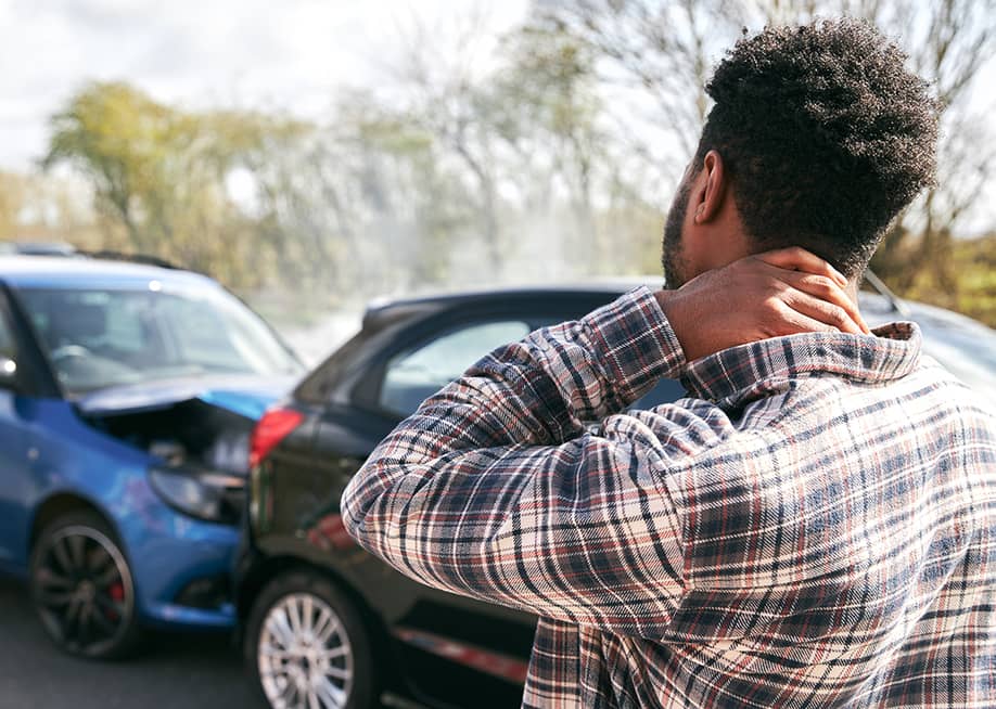 A stressed young man looking at the damage his car caught after an accident. — Southworks // Shutterstock