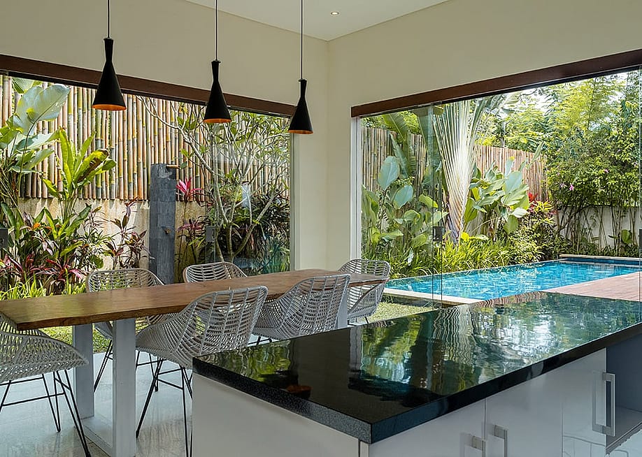 A modern kitchen with a black countertop and a large window overlooking a pool. — Faiz Dila // Shutterstock