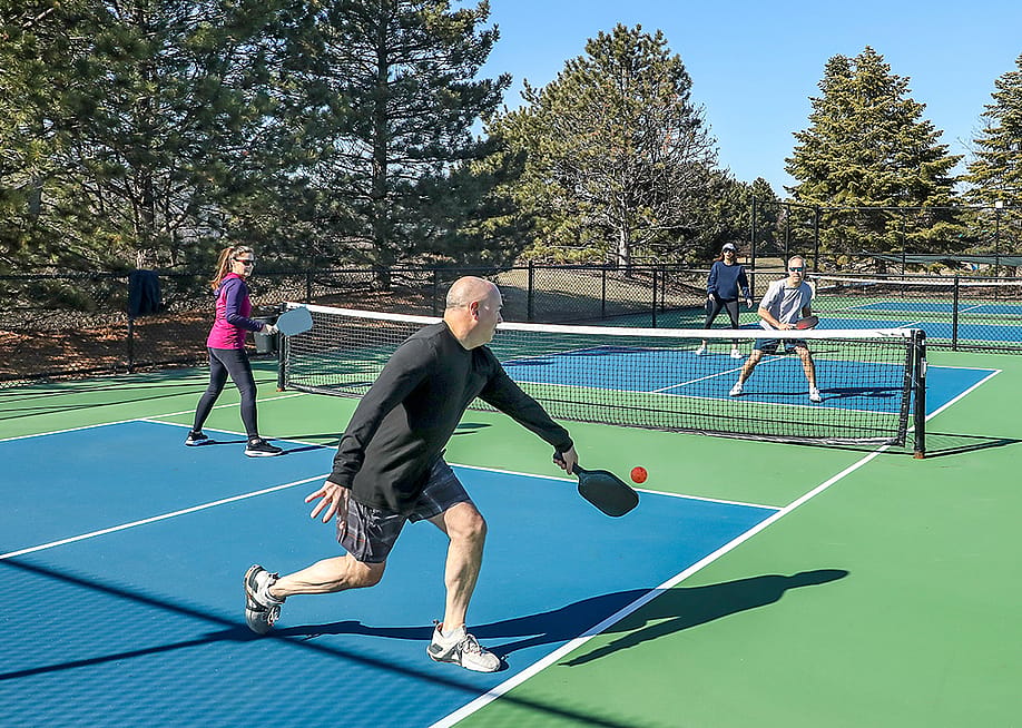 A player hitting a backhand stroke during a pickleball doubles game in spring. — pics721 // Shutterstock
