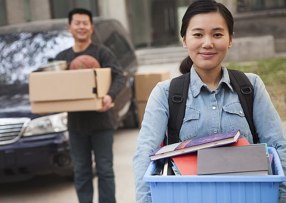 A student carrying her things outside the college dormitory before move-in. — XiXinXing // Shutterstock