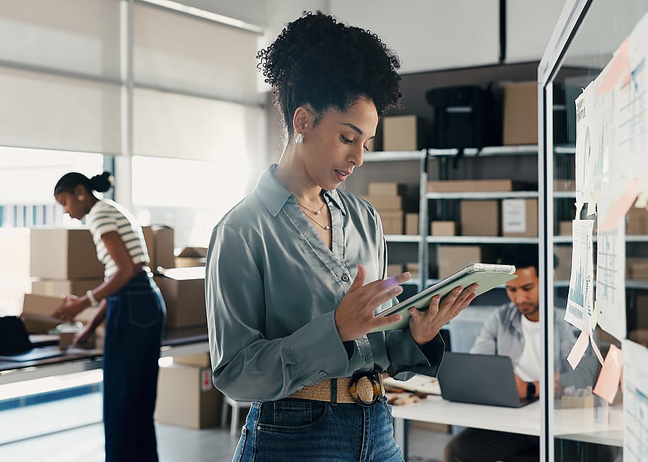A female employee at a logistics team checking on orders. — PeopleImages // Shutterstock