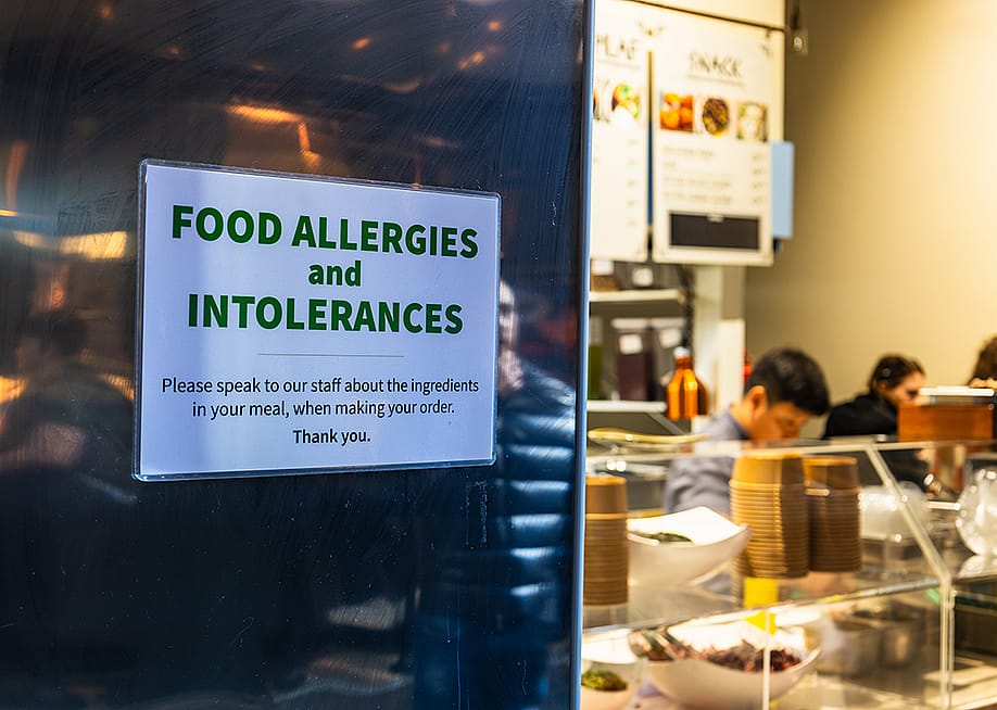 A food allergy and intolerance sign posted on a restaurant's kitchen window for customer reference and safety. — Tartezy // Shutterstock
