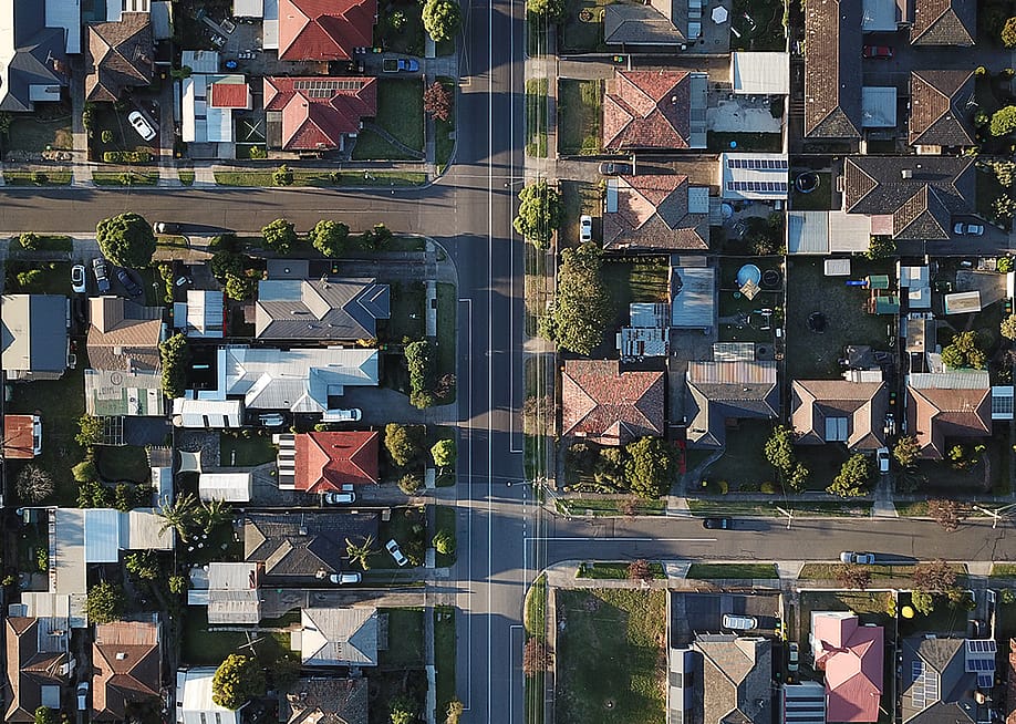 An aerial shot of a downtown street seen through its house rooftops and symmetrical roads during sunset. — Thomas Rumble // Shutterstock