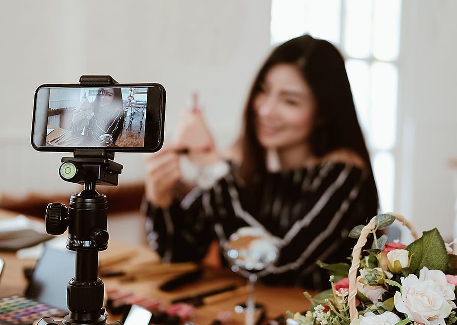 A beauty vlogger broadcasting a makeup tutorial live from her social media account. — 88studio // Shutterstock