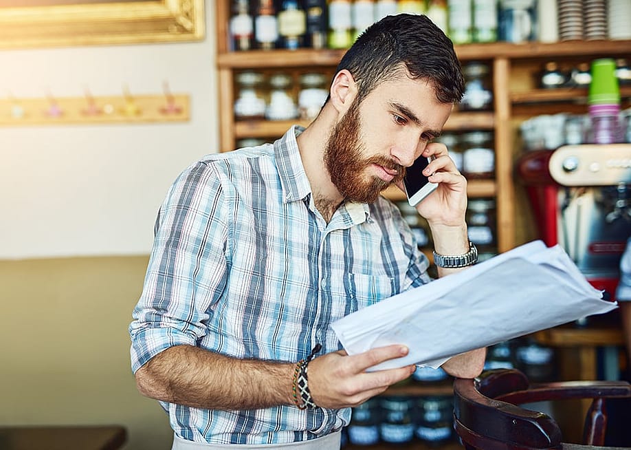 A store manager asking someone for a payment extension of their orders during a phone call. — PeopleImages // Shutterstock