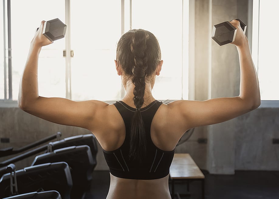 A muscular woman working out with dumbbells — ArNek // Shutterstock
