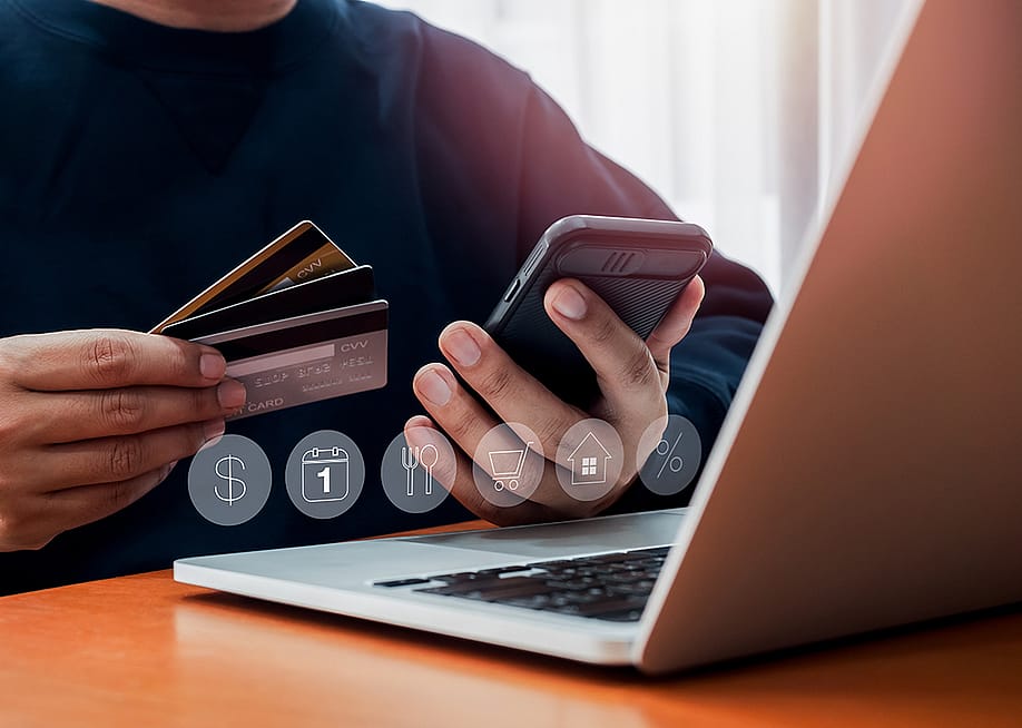 A person holding a few card and his smartphone during a budget review and debt consolidation. — tete_escape // Shutterstock