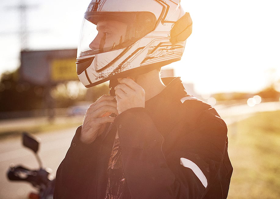 A motorcycle rider fastens his helmet. — Lipik Stock Media // Shutterstock