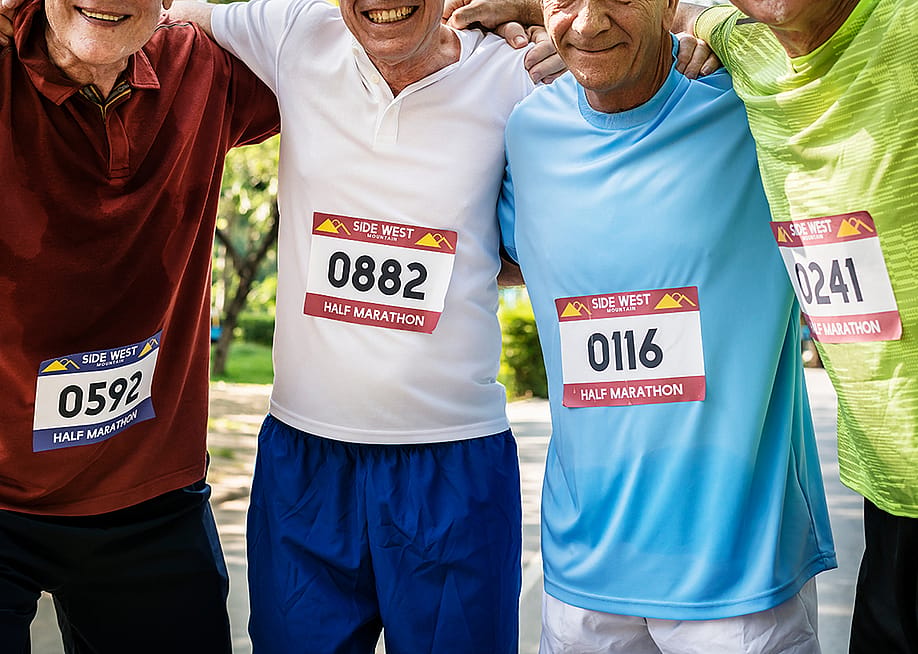 Elderly male runners grouped together with their marathon number tags on their shirts. — Rawpixel.com // Shutterstock
