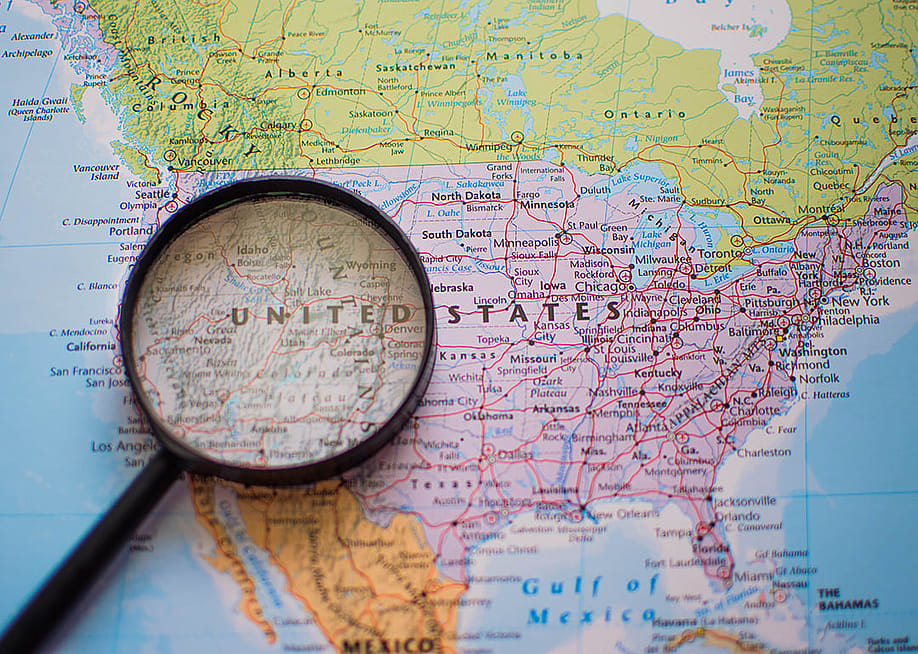A magnifying glass over a US map highlighting the western region. — Neuiiza // Shutterstock