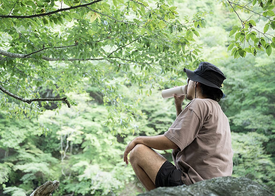 A hiker drinking water during a relaxing break from camping in the mountains. — kapinon.studio // Shutterstock