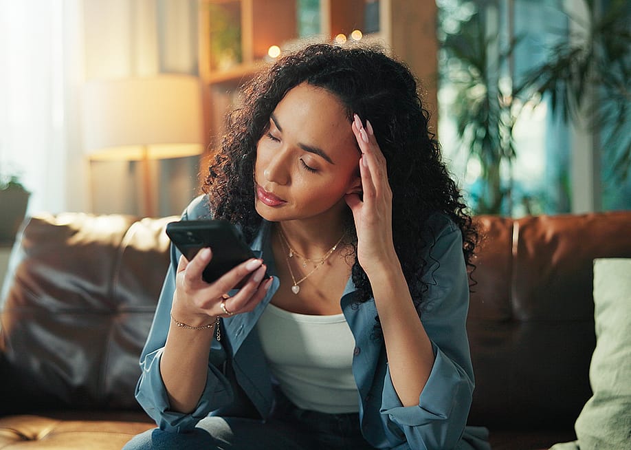 A woman reading a text and experiencing a headache. — PeopleImages // Shutterstock