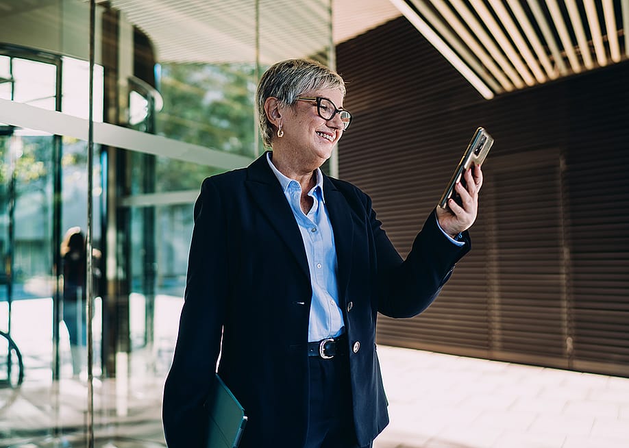 A senior businesswoman smiling at smartphone screen. — GaudiLab // Shutterstock