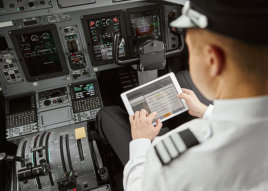 A pilot using a digital display tablet inside the cockpit before an airplane's departure flight. — Ivan Dudka // Shutterstock
