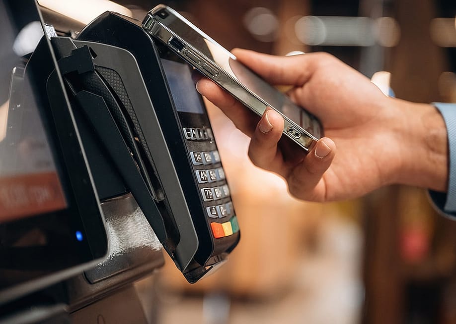 Person using wireless payment via phone in a payment terminal. — Standret // Shutterstock
