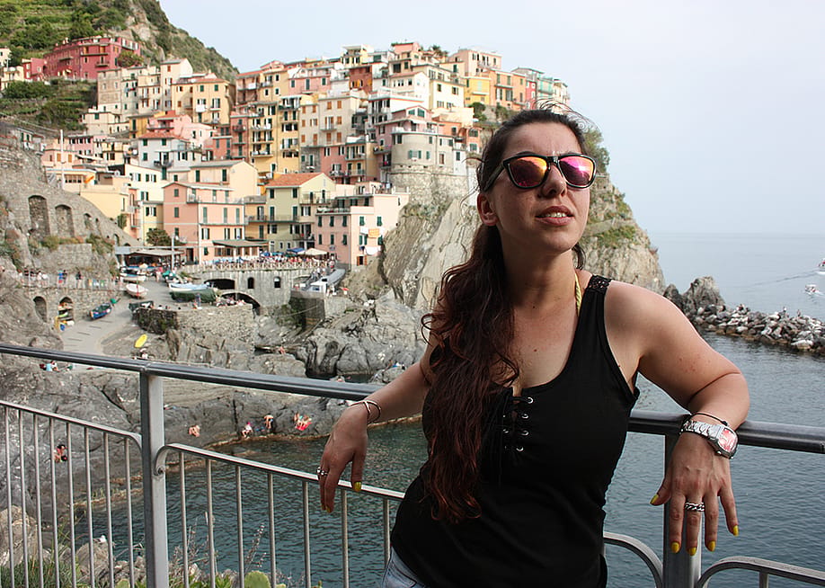 A female tourist with the Cinque Terre coast in Italy in her background. — alessia_penny90 // Shutterstock