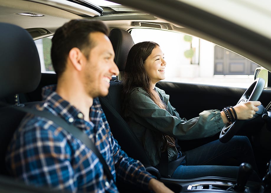 A father guiding her teenage daughter on how to drive. — antoniodiaz // Shutterstock