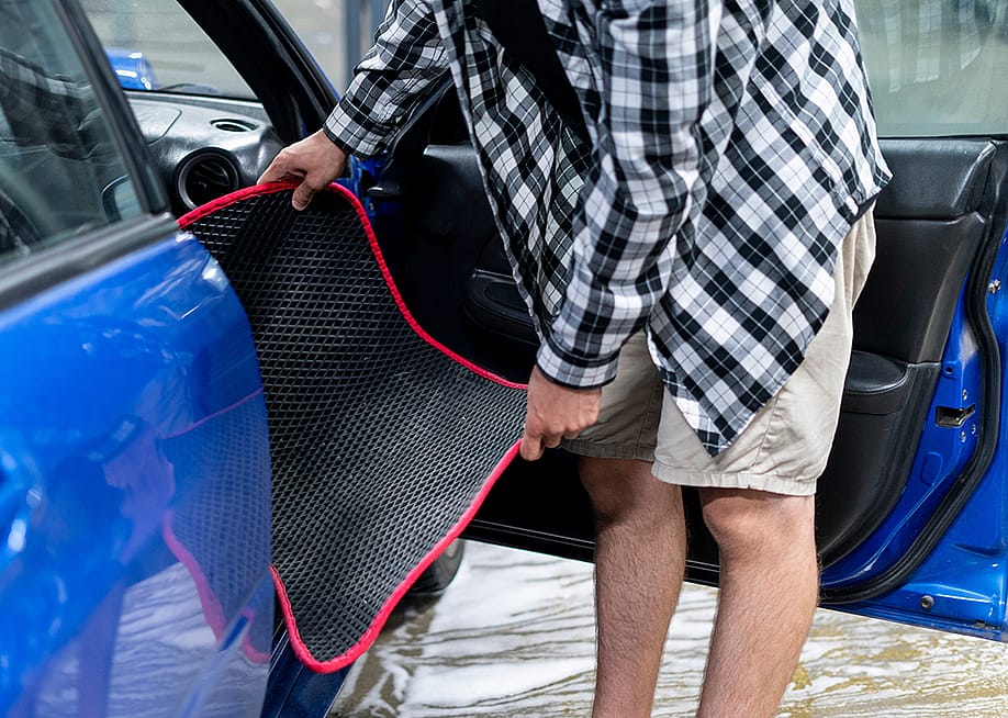 Man taking out dirty mat from car interior. — x662nh // Shutterstock