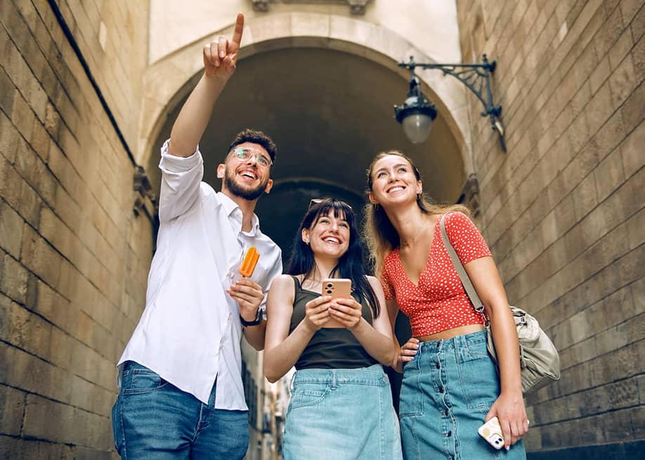 A group of three friends out and about sightseeing in a city. — Josep Suria // Shutterstock