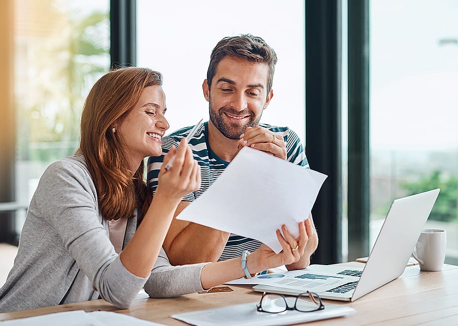 A married couple reviewing their budget and personal documents in preparation for a home loan. — PeopleImages // Shutterstock