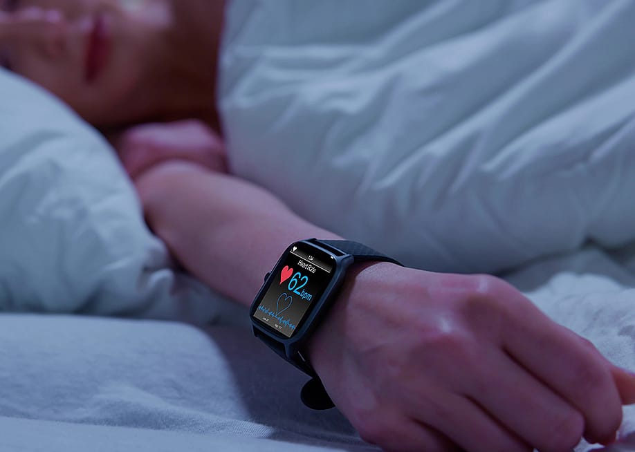 Person in bed wearing a smartwatch with heart rate monitor. — Andrey_Popov // Shutterstock