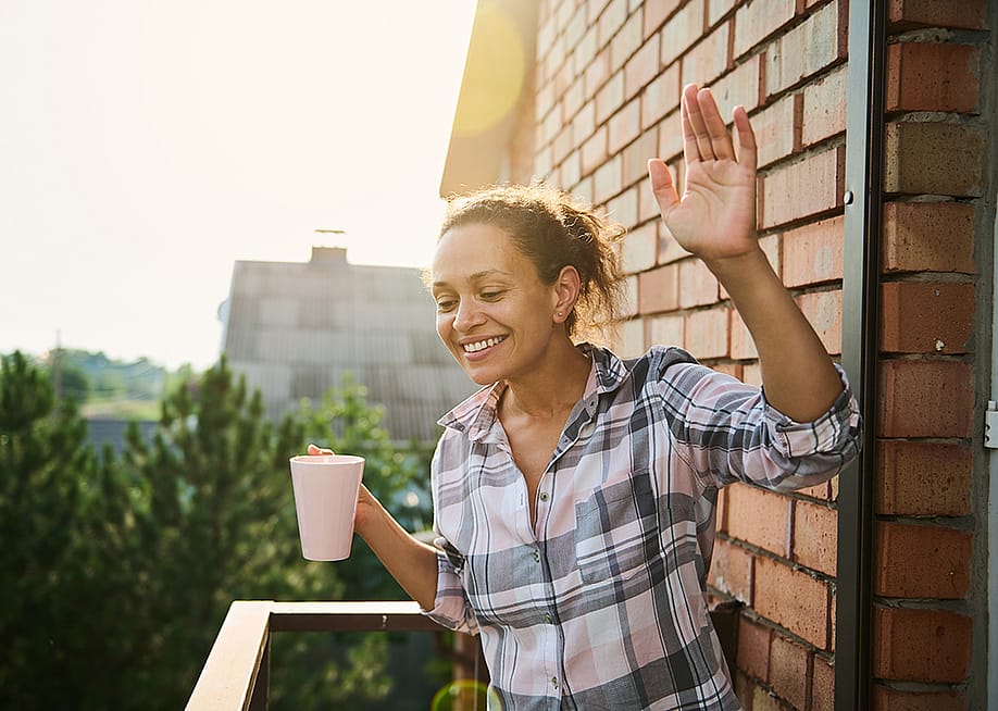 A woman greeting people from her balcony in the morning. — Taras Grebinets // Shutterstock