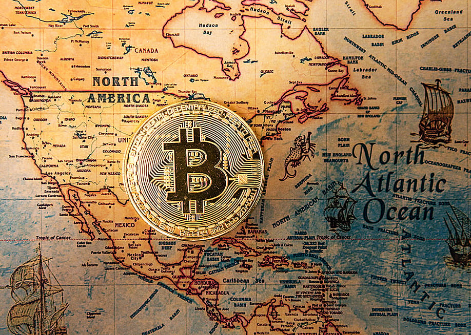 A crypto currency bitcoin symbol centered on an ancient map of North America and North Atlantic ocean. — ilolab // Shutterstock