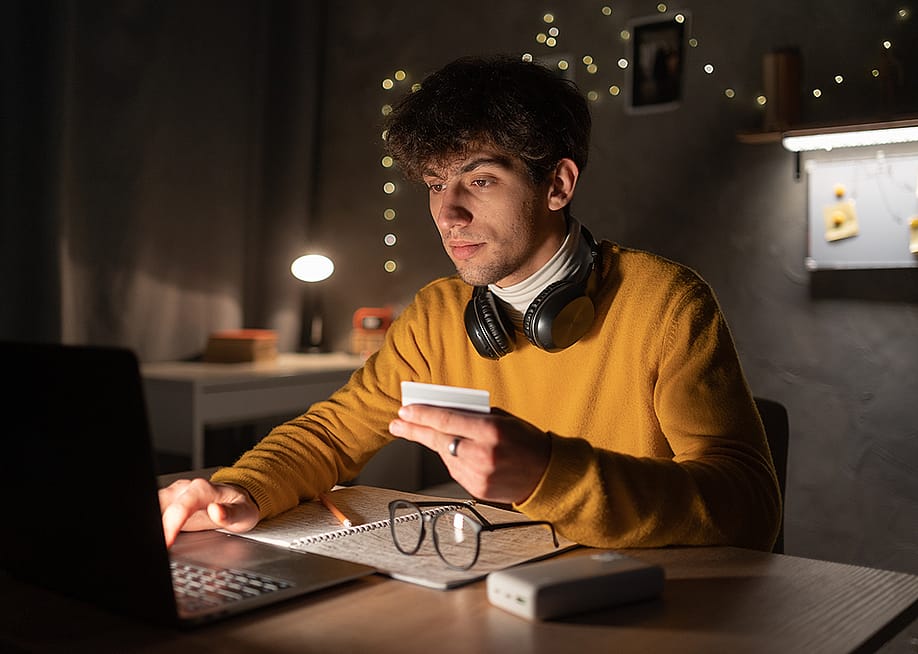 A male college student up at night making an online purchase. — Lysenko Andrii // Shutterstock