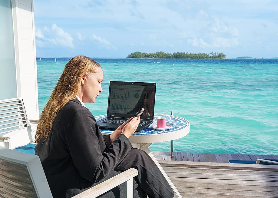 A young woman checking at dashboards and email while on a beach vacation. — Igor Link // Shutterstock
