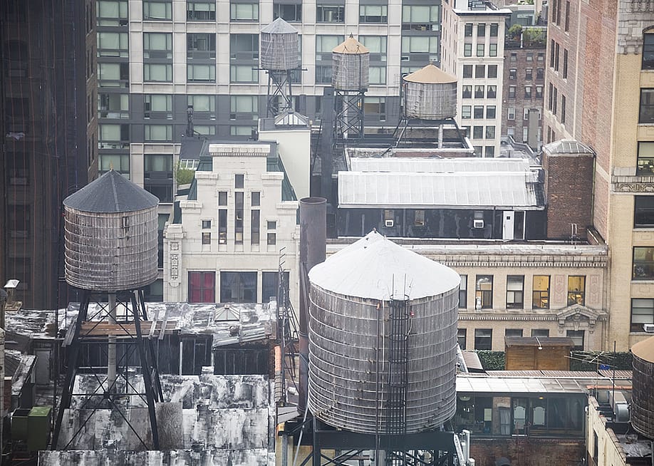 Water towers seen on the rooftops skyline of New York City, USA. — GJones Creative // Shutterstock