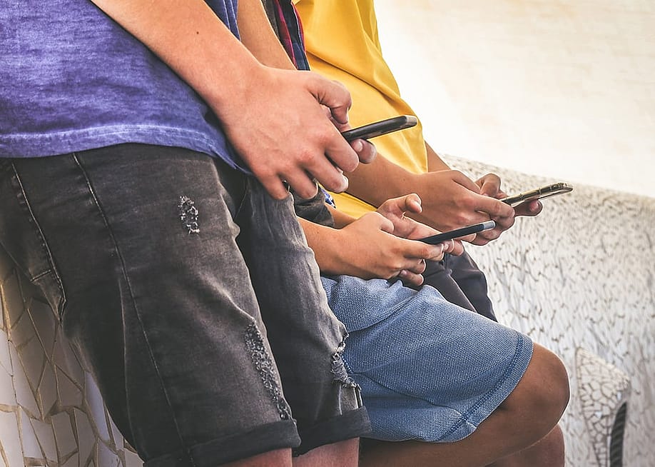 A group of teenagers using their smartphones outdoors. — Nomads Image Lab // Shutterstock