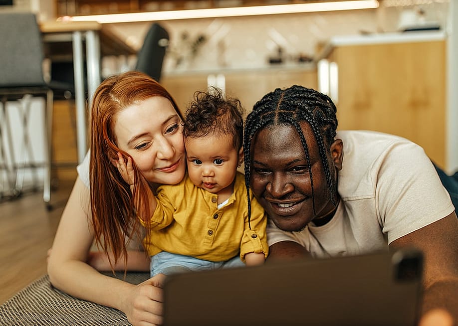 A happy couple with their young child watching something from a digital tablet. — Branislav Nenin // Shutterstock