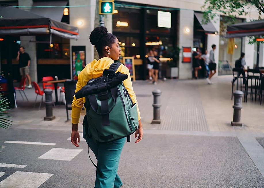 A woman with a backpack crossing a road. — GaudiLab // Shutterstock