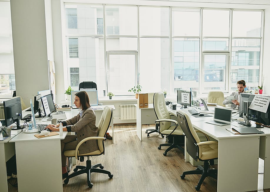 Employees sitting in a half-empty office. — Pressmaster // Shutterstock