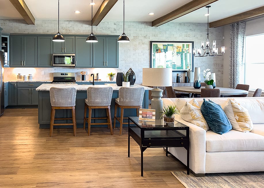 luxury open living space with cream-colored sectional, pillows, and kitchen in the background. — Arina P Habich // Shutterstock