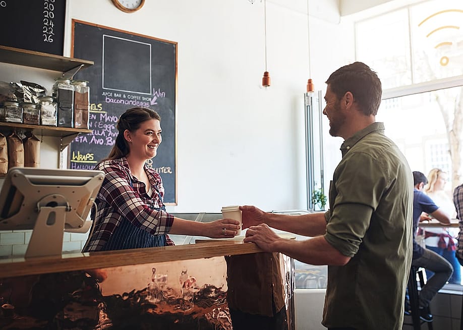 Barista giving a customer's cup of coffee — PeopleImages // Shutterstock