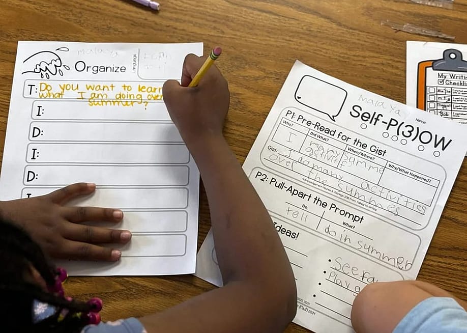 A first grader at Sand Creek Elementary fills out a worksheet to help organize thoughts before writing a paragraph about her summer plans. The Douglas County School District adopted a method of teaching writing that emphasizes structure and planning. — Jackie Mader for The Hechinger Report