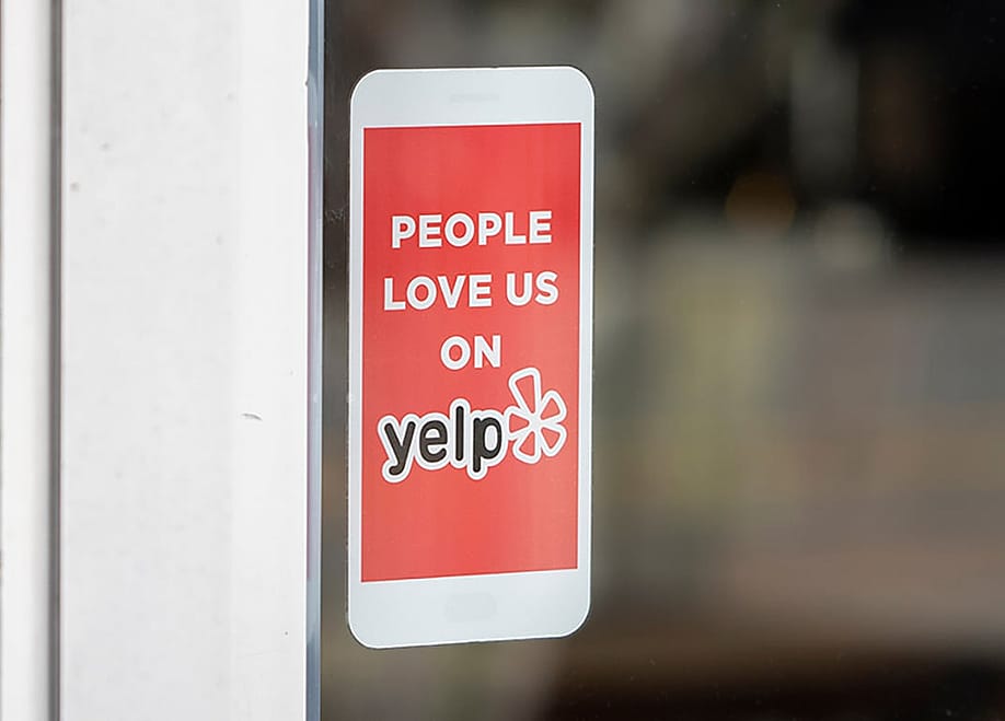 A 'People love us on Yelp' sticker at the entrance of a restaurant. — Tada Images // Shutterstock