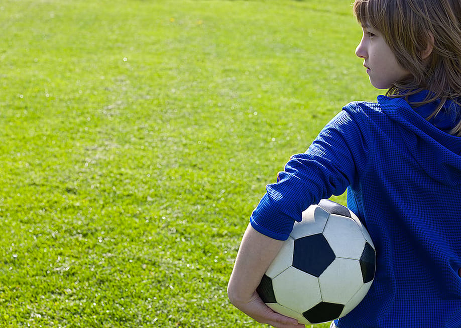 A young boy holding a soccer ball in a park field. — Tretyakov Viktor // Shutterstock