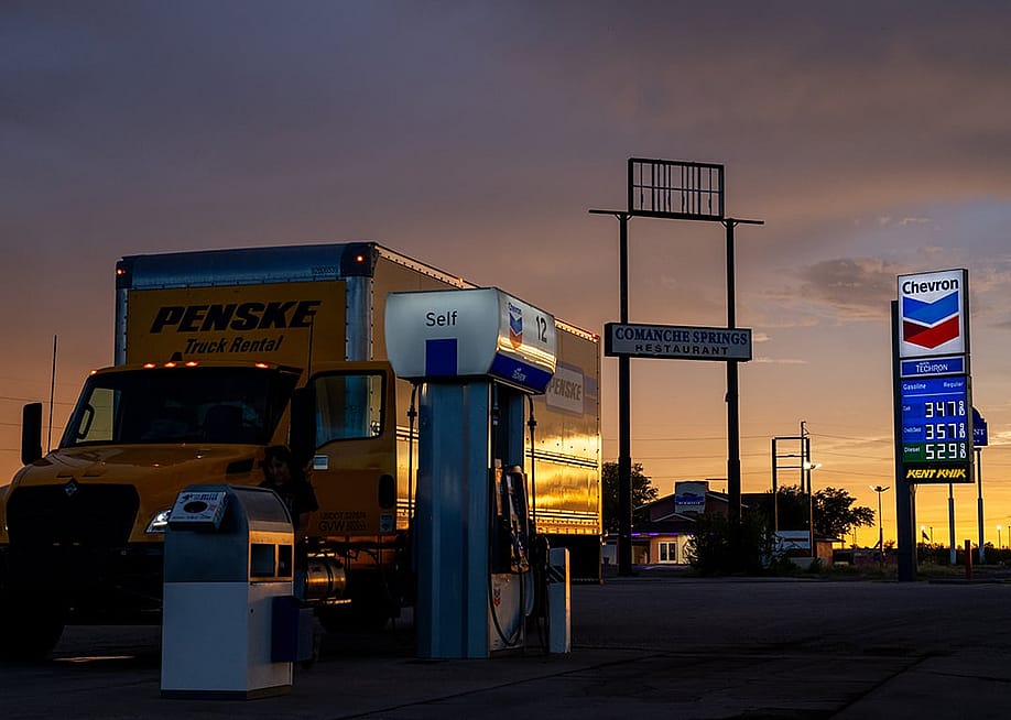 A truck getting fuel at a gasoline station with gas and diesel prices displayed at the back. — Brandon Bell // Getty Images